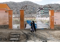 A woman with a girl walks past the site of a car bomb blast that targeted schoolgirls in Kabul, Afghanistan May 10, 2021.