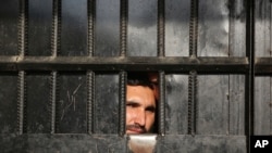 Taliban prisoners watch through the door inside a prison after an attack in the city of Jalalabad, east of Kabul, Afghanistan, Aug. 3, 2020.