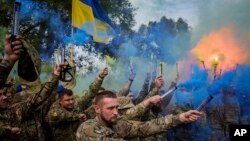 Ukrainian servicemen of the Azov brigade light flares during the funeral ceremony of a fallen comrade in Travkine, Chernihiv region, Ukraine, Oct. 4, 2024. 