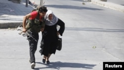 Seorang anggota Laskar Pembebasan Suriah membantu seorang perempuan menyeberang jalan di Aleppo (foto: dok). Seorang wartawan Jepang tewas saat menyertai pemberontak Suriah di Aleppo. 