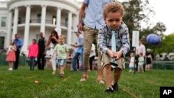 FILE - Eggs fly as children get a little help from parents to cross the finish line during the White House Easter Egg Roll on the South Lawn of the White House in Washington, April 17, 2017, hosted by President Donald Trump and first lady Melania Trump.