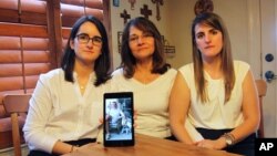 Dennysse Vadell (tengah), istri eksekutif perminyakan Tomeu Vadell yang ditahan di Venezuela, didampingi kedua putrinya, menunjukkan foto suaminya, di Katy, Texas, 15 Februari 2019. 