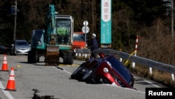 Kola propala kroz rupu koja se otvorila od zemljotresa pored Udžime u Išikavi (Foto:REUTERS/Kim Kyung-Hoon)