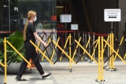 A woman wearing a face mask approaches a temperature screening area of an office building as a preventive measure against the coronavirus spread, in Singapore, March 20, 2020.