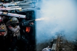 A police officer fires his tear gas launcher during a clash with student protesters in Bandung, West Java, Indonesia, Sept. 30, 2019.