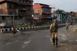 FILE -Indian Paramilitary soldiers drag barbwire as they prepare to impose curfew in Srinagar, Indian controlled Kashmir, Aug. 7, 2019.