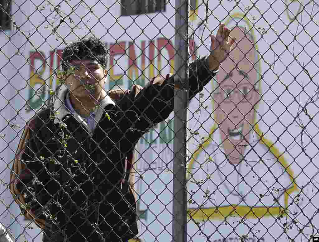 An inmate stands behind the fence at Palmasola prison, decorated with a mural of Pope Francis that reads in Spanish: &quot;Welcome who comes in the name of the Lord&quot; as the pontiff visited prisoners in Santa Cruz, July 10, 2015.