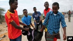 People carry away the body of a man killed in a suicide car bomb attack, near the defense ministry compound in Mogadishu, April 9, 2017. 