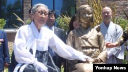 지난해 7월 위안부 피해자 김복동 할머니가 미국 글렌데일 시립 도서관 앞에서 제막한 평화의 소녀상 옆에 앉아 소녀상을 쓰다듬고 있다. (자료사진)