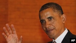 U.S. President Barack Obama waves at reporters as he walks after a plenary session of the East Asia Summit in Nusa Dua, Bali, November 19, 2011.