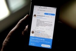 FILE - A man reads tweets by Indian celebrities on his mobile phone in New Delhi, India, Feb. 4, 2021.