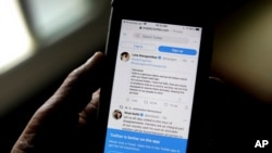 FILE - A man reads tweets by Indian celebrities on his mobile phone in New Delhi, India, Feb. 4, 2021.