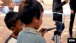 កុមារា​ពីរ​នាក់​សាកល្បង​ប្រើប្រាស់​ទូរស័ព្ទ​ទំនើប​នៅ​ឯ​សាលារៀន​របស់​ពួកគេ ដែល​ស្ថិត​ក្នុង​ឃុំ​បិតត្រាំង ស្រុក​ព្រៃនប់ ខេត្ត​ព្រះសីហនុ កាល​ពី​ថ្ងទី១៩ ខែធ្នូ ឆ្នាំ២០១៥។​ (អូន ឆេងប៉រ/VOA) 