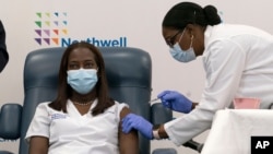 Sandra Lindsay, left, a nurse at Long Island Jewish Medical Center, is inoculated with the Pfizer-BioNTech COVID-19 vaccine by Dr. Michelle Chester, Dec. 14, 2020, in the Queens borough of New York.