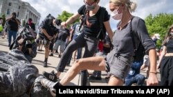 People take turns stomping the Christopher Columbus statue after it was toppled in front of the Minnesota State Capitol in St. Paul, Minn., on Wednesday, June 10, 2020. (Leila Navidi/Star Tribune via AP)