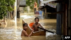 Anak-anak menggunakan lemari es sebagai perahu untuk menyeberangi gang banjir di Candaba, Pampanga, utara Manila, Filipina, 18 Desember 2015, sebagai ilustrasi. (Foto: AFP)
