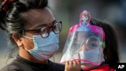 A Nepalese woman and her daughter wearing face masks as a precaution against the coronavirus watch devotees pull a chariot during the Rato Machindranath chariot festival in Lalitpur, Nepal, May 15, 2021.