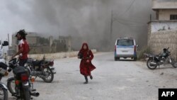 지난 5월 시리아 이들리브주 파르 루마에서 시리아 여성이 정부군의 공습을 피해 달리고 있다. 