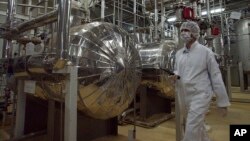 ইরানের ইসফাহান শহরের বাইরে একটি ইউরেনিয়াম কনভার্সন কেন্দ্রের এক অংশ দিয়ে সুরক্ষা-পোশাক পরে হেঁটে যাচ্ছেন ইরানের এক নিরাপত্তা কর্মকর্তা। ফাইল ফটো।