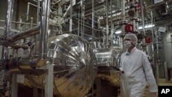 FILE - Seorang pejabat keamanan Iran dengan pakaian pelindung berjalan melalui sebagian Fasilitas Konversi Uranium di luar kota Isfahan, Iran. (Vahid Salemi, File/AP)