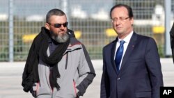 L’ex-otage Marc Feret, à gauche, est accueilli après sa libération par le président François Hollande en France, à la base aérienne militaire de Villacoublay, dans la périphérie de Paris, 30 octobre 2013. 