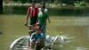 Flood victims ride a bamboo raft over a flooded road to receive relief items from private donors in Thabaung township, Ayeyarwaddy delta, Myanmar, Aug. 29, 2015.