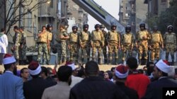 Egyptian Army soldiers stand guard atop a concrete block barricade on the street between Tahrir Square and the interior ministry in Cairo, Egypt, Nov. 24, 2011