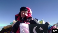 Samina Baig, perempuan pendaki gunung asal Pakistan, memegang bendera nasionalnya di puncak Gunung Everest, Nepal, 19 Mei 2013. (AFP/PAKISTAN Youth OUTREACH)