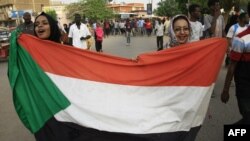 资料照：苏丹妇女2019年6月30日在首都喀土穆的集会上举着国旗游行。