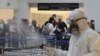 FILE - Passengers line up as workers wearing protective gear spray disinfectant as a precaution against the coronavirus outbreak, in the departure terminal at the Rafik Hariri International Airport, in Beirut, Lebanon, March 5, 2020.