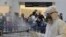 FILE - Passengers line up as workers wearing protective gear spray disinfectant as a precaution against the coronavirus outbreak, in the departure terminal at the Rafik Hariri International Airport, in Beirut, Lebanon, March 5, 2020.