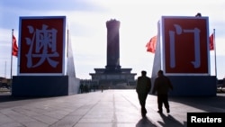 Turis berjalan menuju dua huruf raksasa China bertuliskan "Macau" yang dipasang di depan Monumen Pahlawan Rakyat di tengah Lapangan Tiananmen pada 16 Desember. (Foto: Reuters)