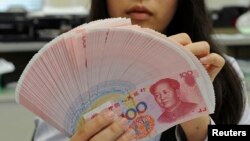 An employee counts Chinese yuan notes inside a bank in Taipei, Feb. 6, 2013.