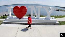 FILE - A woman walks a small dog near a sign at Finger Lakes Welcome Center on the banks of Lake Geneva in Geneva, N.Y. 
