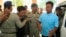 Chay Sarith, second left, and Mao Hoeun, second right in light blue shirt, suspected attackers who are accused of beating two opposition lawmakers along with another man, are escorted by police officers at Phnom Penh Municipal Court in Phnom Penh, Cambodia, Wednesday, Nov. 4, 2015. Three suspects of the assault outside of the National Assembly last week made confessions on Tuesday, according to a government statement released late Tuesday. (AP Photo/Heng Sinith)