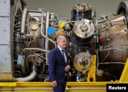German Chancellor OIaf Scholz stands next to a gas turbine meant to be transported to the compressor station of the Nord Stream 1 gas pipeline in Russia during his visit to Siemens Energy's site in Muelheim an der Ruhr, Germany, August 3, 2022.