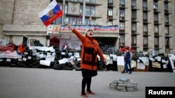 A pro-Russia protester shouts slogans as she waves a Russian flag outside a regional government building in Donetsk, in eastern Ukraine April 23, 2014. 