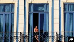 FILE - A tourist looks out from his hotel room's balcony in Havana, Cuba.