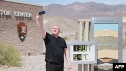 Seorang pengunjung mengambil selfie di samping tampilan digital suhu udara di Taman Nasional Death Valley di California yang mencapai lebih dari 54 Celcius, saat gelombang panas pada 16 Juli 2023 lalu (foto: dok).