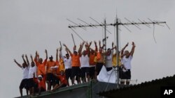 FILE - Inmates at the Puraquequara prison stand on a water tower as they protest against bad conditions and restrictions on family visits put in place to curb the spread of the new coronavirus, in Manaus, Brazil, May 2, 2020. 
