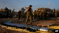 اسرائیلی فوجی اتوار، 31 دسمبر، 2023 کو غزہ کی سرحد کے قریب جنوبی اسرائیل میں ایک اسٹیجنگ ایریا میں ایک ٹینک پر گولے لوڈ کر رہے ہیں۔