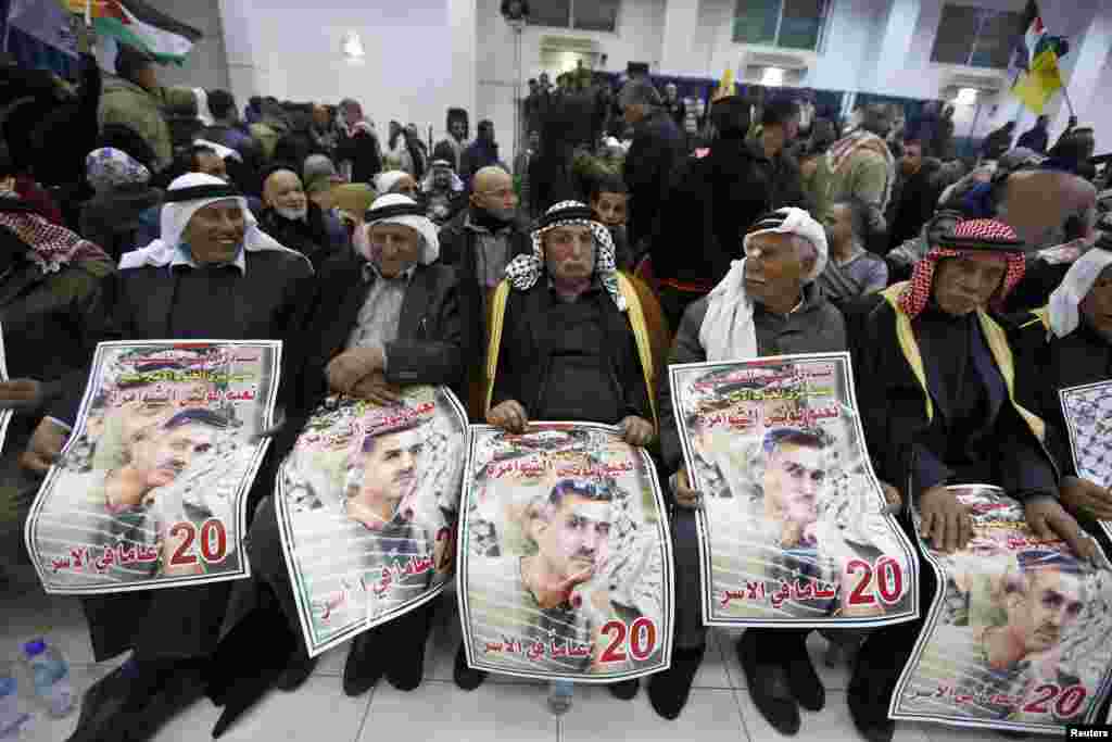 Palestinians hold posters depicting Palestinian prisoner Naim Shawamreh as they wait for the released prisoners to arrive in Ramallah, West Bank, Dec. 30, 2013.