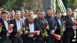 People hold flowers as they gather along the road to watch the funeral procession of President Islam Karimov in Samarkand, Uzbekistan, Saturday, Sept. 3, 2016.