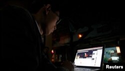 FILE - A Vietnamese internet activist posts a status on Facebook at a cafe in Hanoi, Nov. 27, 2013.