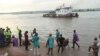 FILE - People that have been deported from Congo's capital Brazzaville, seen in background, arrive by river boat in Kinshasa, Democratic Republic of Congo, April 29, 2014.