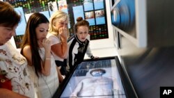 In this April 12, 2018, photo, people look at an interactive exhibit at the Crime Lab Experience in the Mob Museum in Las Vegas. For years the museum has showcased the area's storied past in organized crime, but visitors can now also enjoy a speakeasy, a use of deadly force training experience, and an interactive crime lab exhibit. (AP Photo/John Locher)