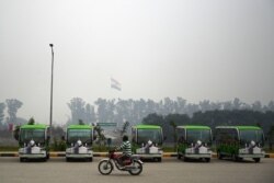 A Pakistani motorcyclist rides past golf carts, which are for Sikh pilgrims, at the immigration center near the Shrine of Baba Guru Nanak Dev at the Gurdwara Darbar Sahib, in the Pakistani town of Kartarpur, near the Indian border, Nov. 6, 2019.