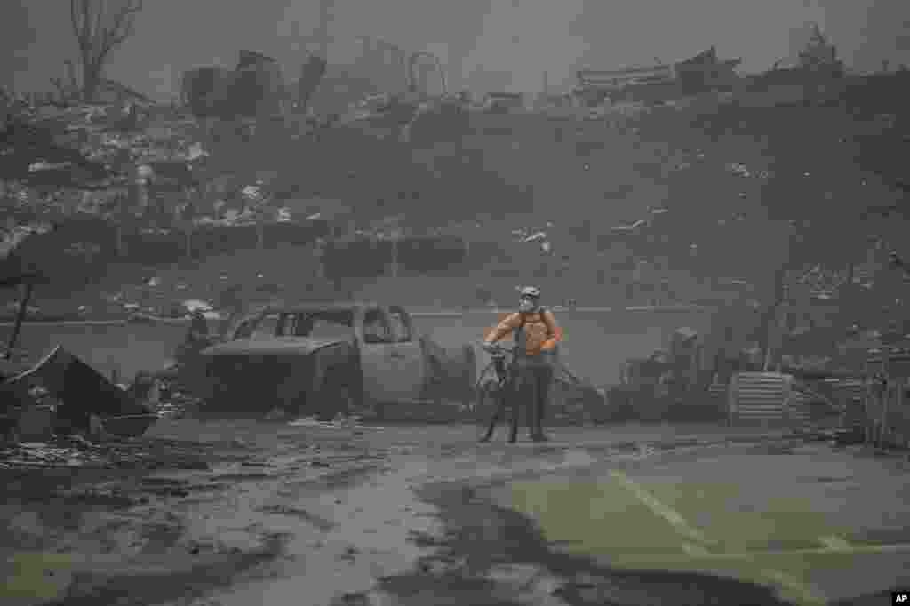 A man walks his bike among the ruins left behind by the Palisades Fire in the Pacific Palisades neighborhood of Los Angeles, California.&nbsp;Multiple massive wildfires are tearing across the Los Angeles area with devastating force. The flames drove residents to make desperate escapes from burning homes through ferocious winds and towering clouds of smoke. At least two people have died and numerous have been injured.
