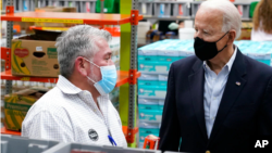 拜登总统在休斯顿一处食物银行与一名义工交谈。(2021年2月26日)