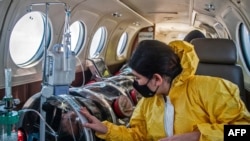 Andrea Lara (kanan) melihat ayahnya Juan Carlos Lara (59), pasien COVID-19, saat dia dipindahkan dengan kapsul keamanan ke ambulans udara dari Iquitos ke Unit Perawatan Intensif Rumah Sakit Rebagliati, di Lima, Peru. (FOto: dok).